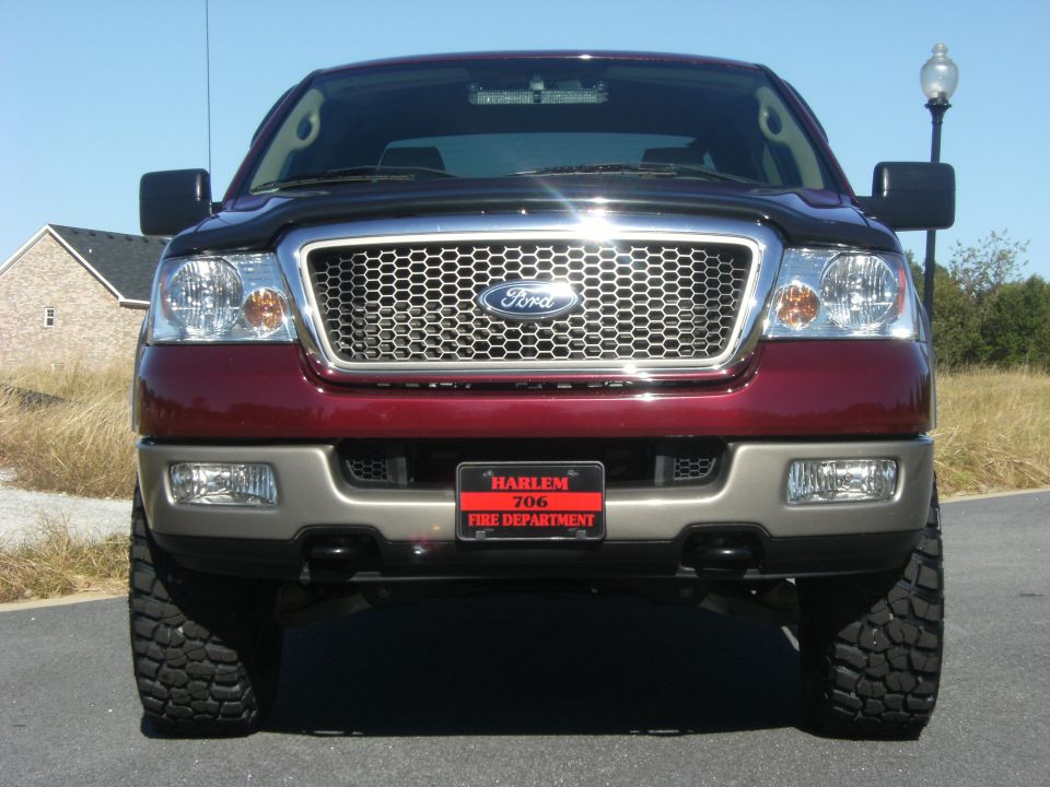 Front view of a dark-red Ford F-150 with chrome honeycomb grille and Harlem Fire Department plate