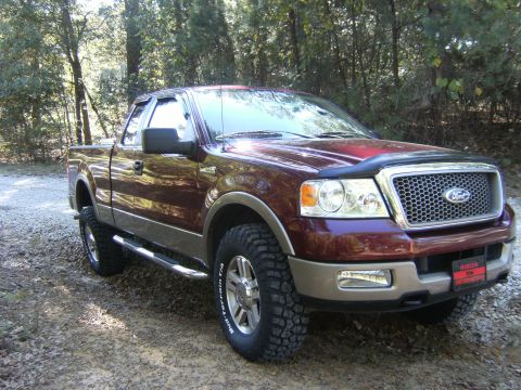 2005 Ford F-150 - A dark maroon/burgundy Ford F-150 extended-cab pickup shown from the front three-quarter angle, with tan lower body cladding, chrome mesh g…
