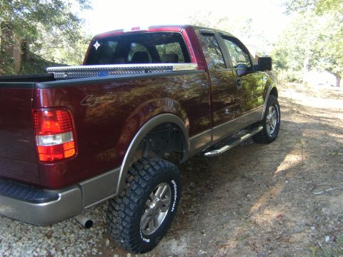 2005 Ford F-150 - Rear three-quarter passenger-side view of a dark maroon Ford F-150 extended-cab pickup with a '4x4' decal, lifted on chrome wheels with BFG…