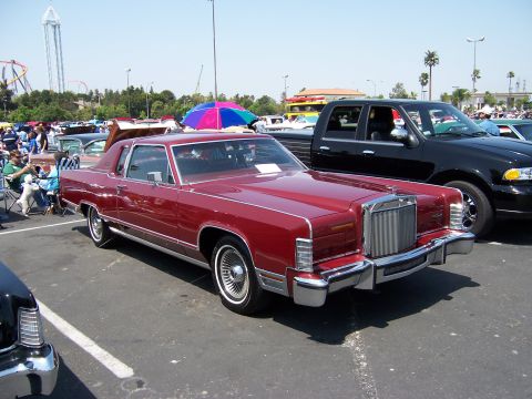 1988 Mercury Grand Marquis - A classic red coupe is parked at an outdoor event with a black pickup truck beside it.