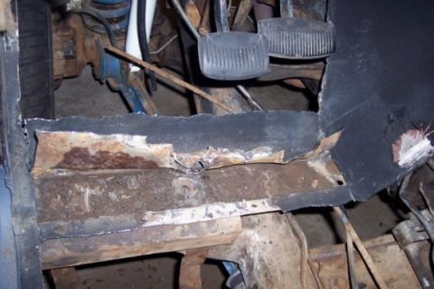 1976 Ford Bronco - Close-up of rusted floor pan and pedals in a vehicle's interior.