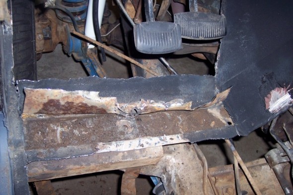 rusted floor pan section with brake and clutch pedals visible