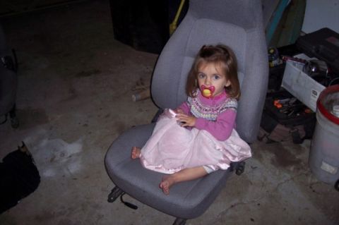 1976 Ford Bronco - A child sits in a car seat, which is the main subject of the photo.