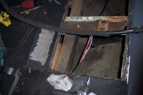 1976 Ford Bronco - Close-up of a vehicle's interior floor showing rust and exposed wiring after a section was cut out.