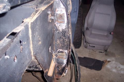 1976 Ford Bronco - A close-up view shows the weathered frame of a vehicle, with a detached seat visible nearby.