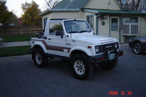1988 Ford Bronco - White 1988 Suzuki Samurai with red stripe detail parked outside a house.