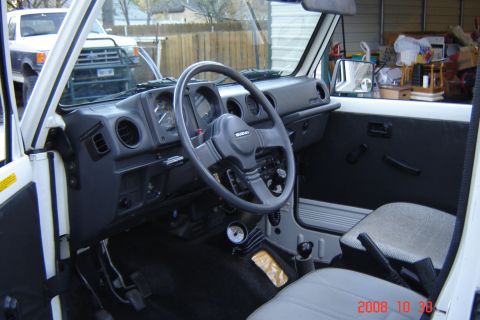 1988 Ford Bronco - Interior view of a white Suzuki Samurai, showing the dashboard and steering wheel.