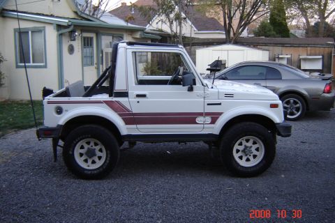 1988 Ford Bronco - Side view of a white 1988 Suzuki Samurai with maroon stripes and a silver Ford Mustang in the background.