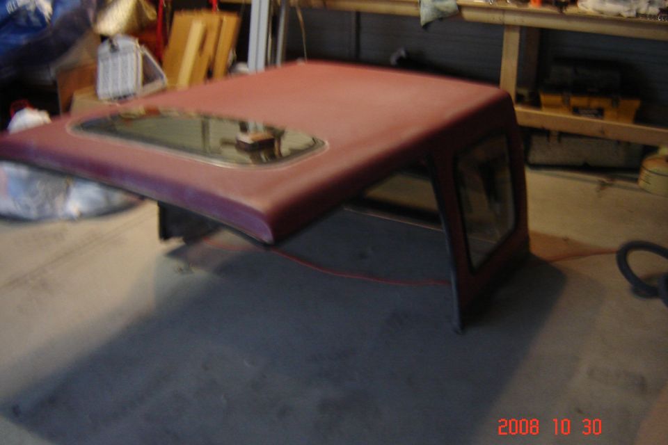 Red hardtop with a sunroof, seen from the side in a garage