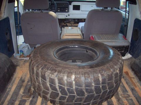 Spare tire on the floor of a vehicle's cargo area, with seats visible in the background