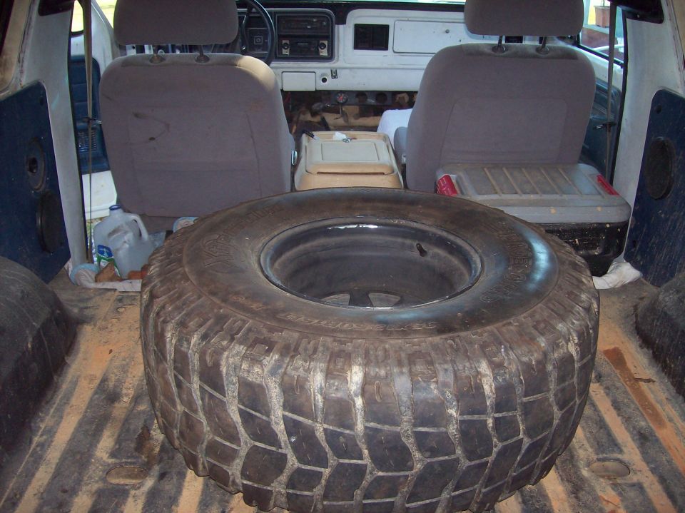Spare tire on the floor of a vehicle's cargo area, with seats visible in the background