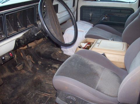 1979 Ford Bronco — Interior shot of a dirty truck cab, showing the dashboard, steering wheel, and seats