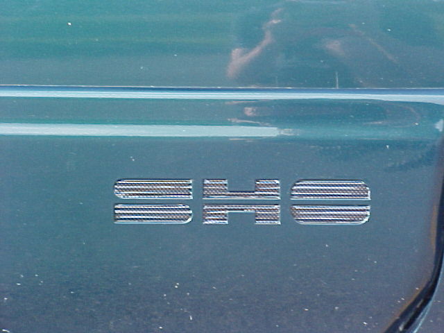 Close-up of chrome SHO badge on dark green Ford Taurus body panel