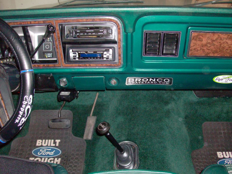 1978 Ford Bronco interior with green carpet, woodgrain trim, and "Bronco Graveyard" sticker