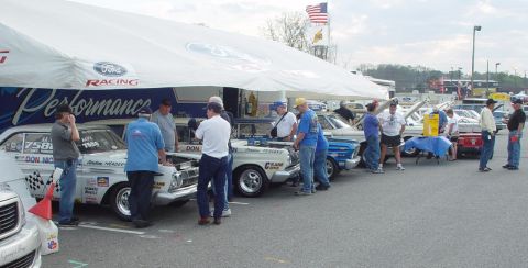 1969 Ford Fairlane - A row of classic race cars are displayed under a large tent with Ford branding.