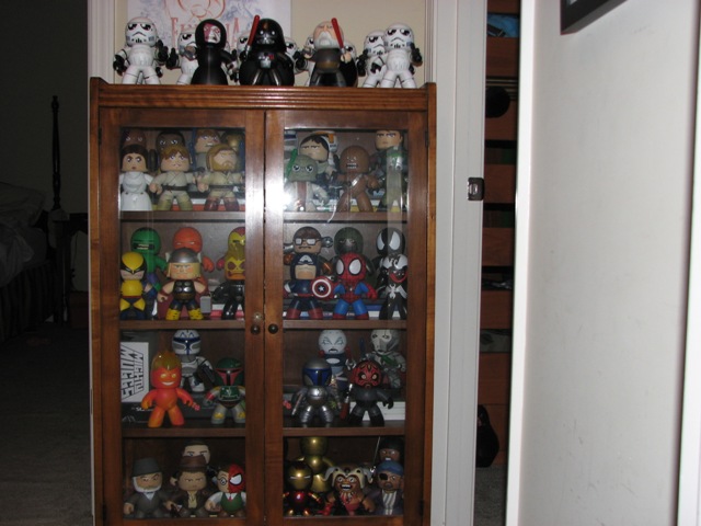 Wooden display cabinet filled with Star Wars and Marvel action figures