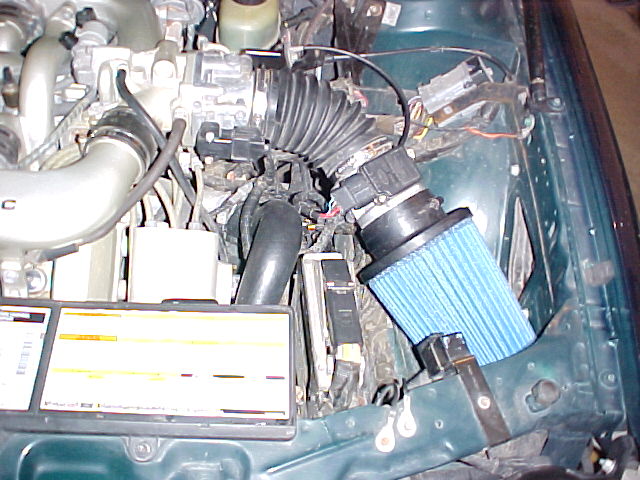 Engine bay with blue aftermarket cone air filter intake on a green car