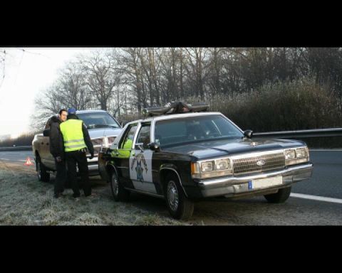 1991 Ford Crown Victoria - Police Crown Victoria and a pickup truck stopped on the side of the road.