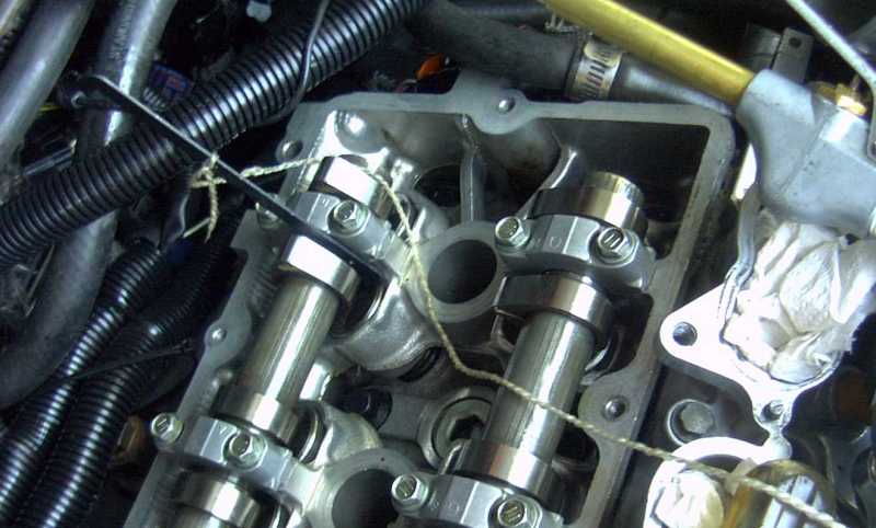 Close-up of engine valve train with camshafts and rocker arms visible. A piece of white cloth is stuffed into a recess