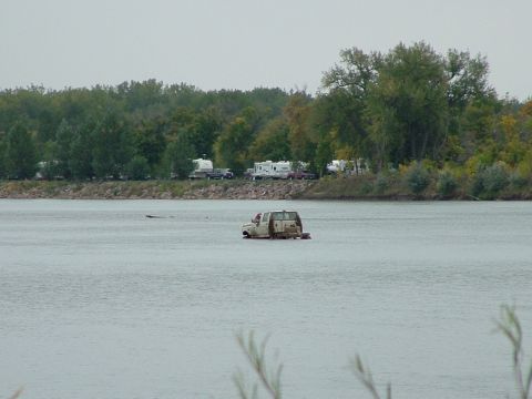 1992 Ford F-350 - A truck floats in the water near a campground with trees in the background.