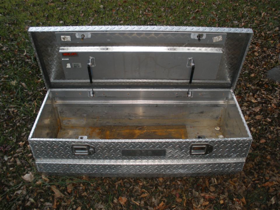 Open aluminum truck tool box with diamond plate pattern. Has two latches and gas struts on lid