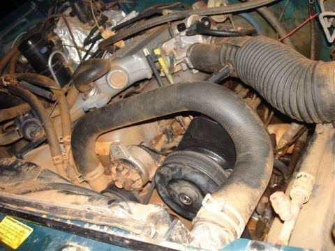 1996 Ford F-150 - Close-up view of a dirty engine bay with various hoses and mechanical components visible.
