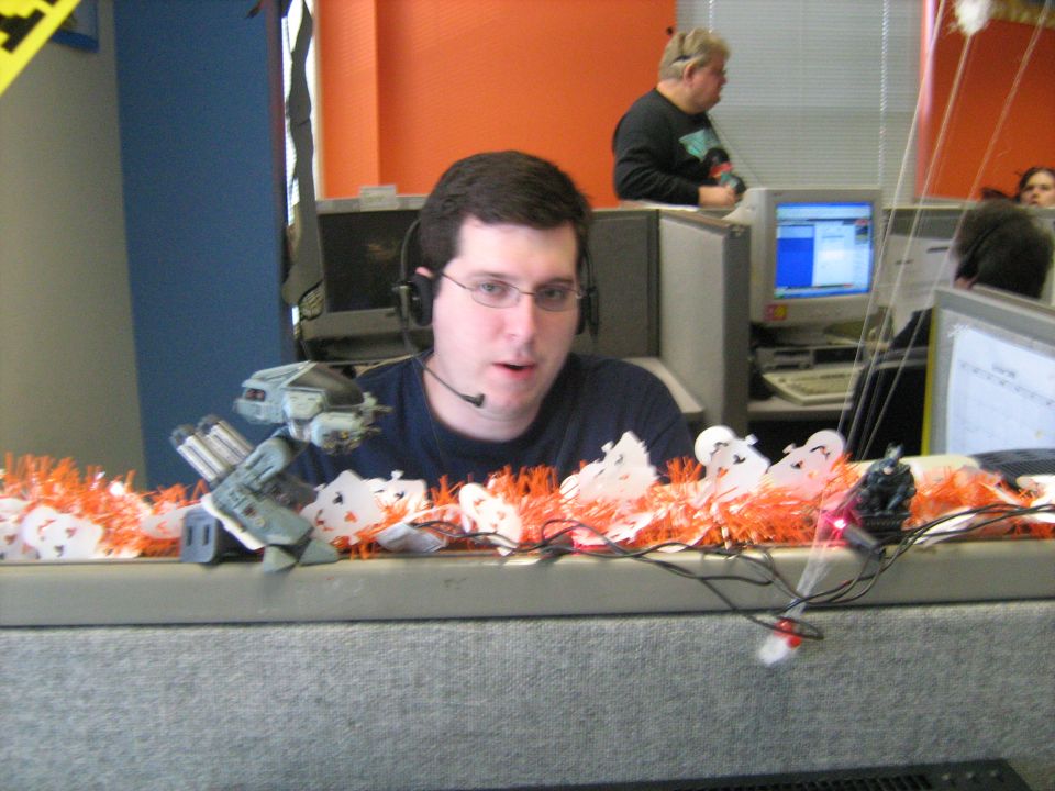 Man wearing a headset at a cubicle desk decorated with orange tinsel