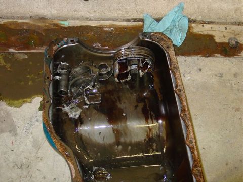 1986 Ford Mustang - This oil pan shows significant internal damage, including a broken piston, indicating a severe engine failure.