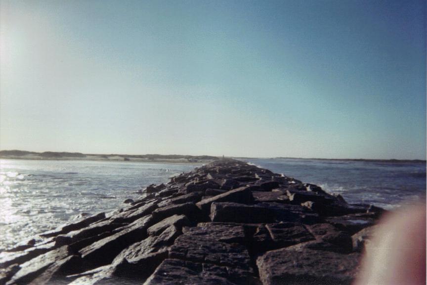 Rock jetty extends into the ocean under a clear blue sky