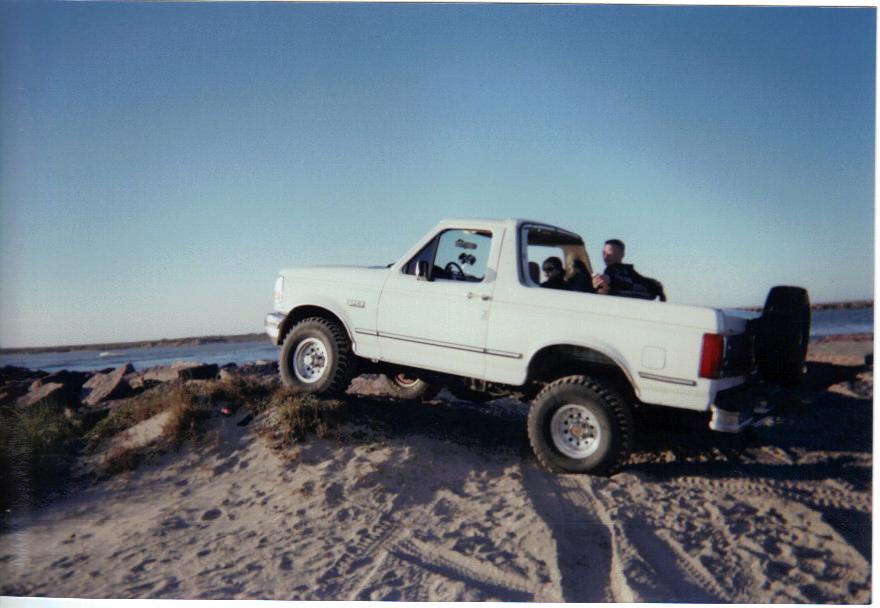 White 1992 Ford Bronco on a sandy dune overlooking the ocean