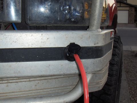 1989 Chevrolet Blazer - A red cable is connected to a port on the front bumper of a vehicle.