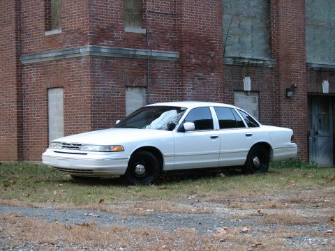 1996 Ford Crown Victoria - White 1995 Ford Crown Victoria parked on grass next to an old brick building.