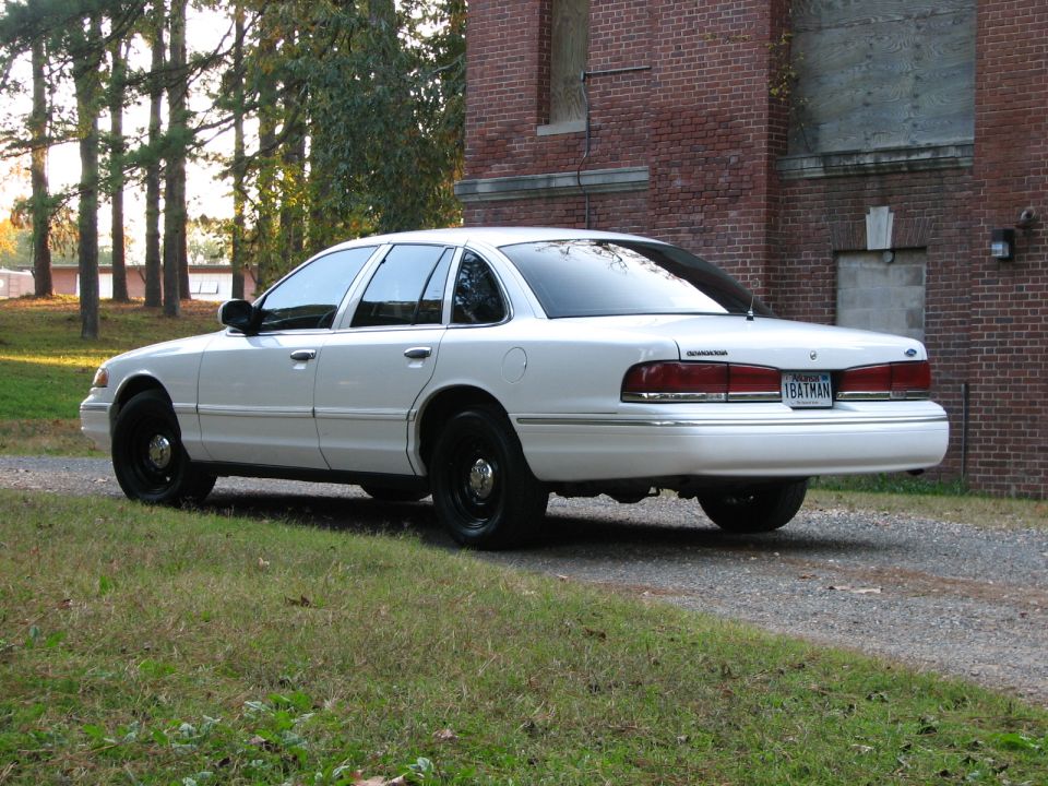 1996 Ford Crown Victoria parked on gravel near brick building, rear 3/4 view. License plate reads 1BATMAN