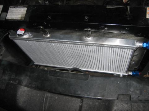 1996 Ford Thunderbird - Close-up of an aftermarket aluminum radiator installed in a vehicle's engine bay.