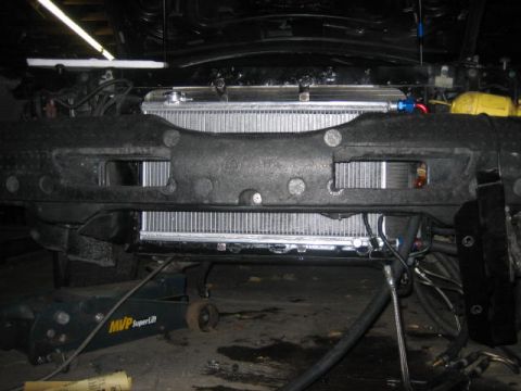1996 Ford Thunderbird - Aftermarket radiator and plumbing visible in the engine bay of a vehicle supported by a jack.