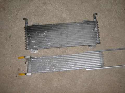 1996 Ford Thunderbird - Two automotive oil coolers are shown side-by-side on a concrete floor.