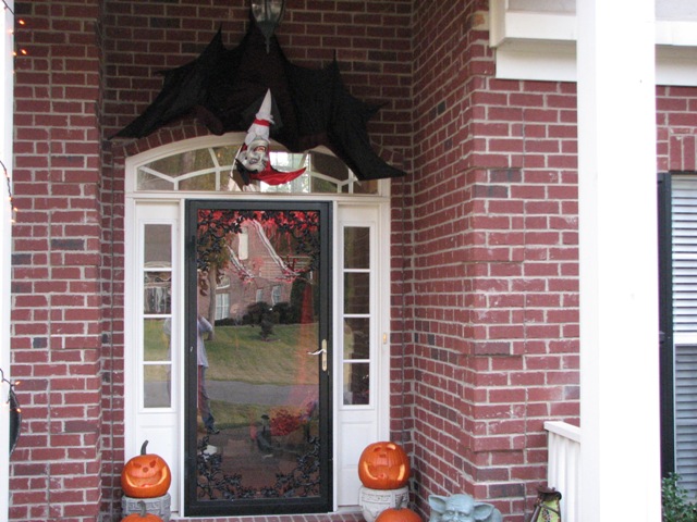 Front door decorated for Halloween with a bat, vampire, and pumpkins