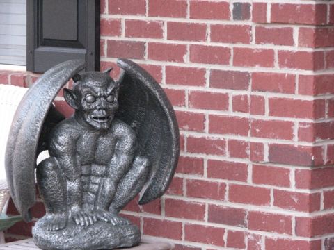 1991 Ford Bronco - A stone gargoyle statue sits on a ledge against a red brick wall. The Supermotors logo is visible in the lower right corner.