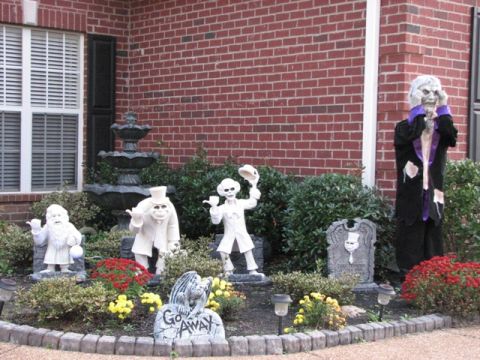 1991 Ford Bronco - Halloween yard decorations feature ghostly figures and a tombstone in front of a brick house.
