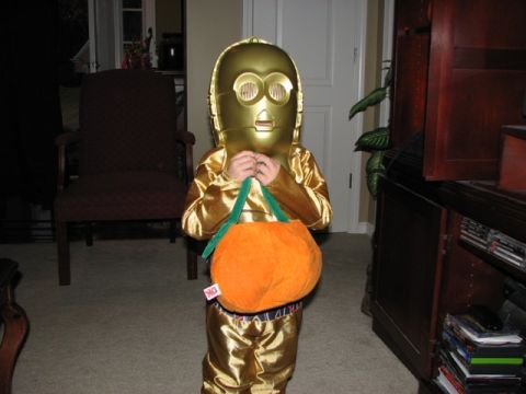 1991 Ford Bronco - A child dressed as C-3PO holds a pumpkin-shaped candy bucket, ready for trick-or-treating.