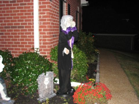 1991 Ford Bronco - A spooky Halloween decoration a vampire figure and a tombstone in front of a brick house.