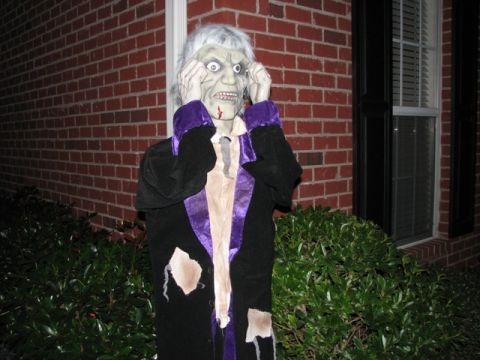 1991 Ford Bronco - A spooky Halloween decoration resembling a zombie stands outside a brick house.
