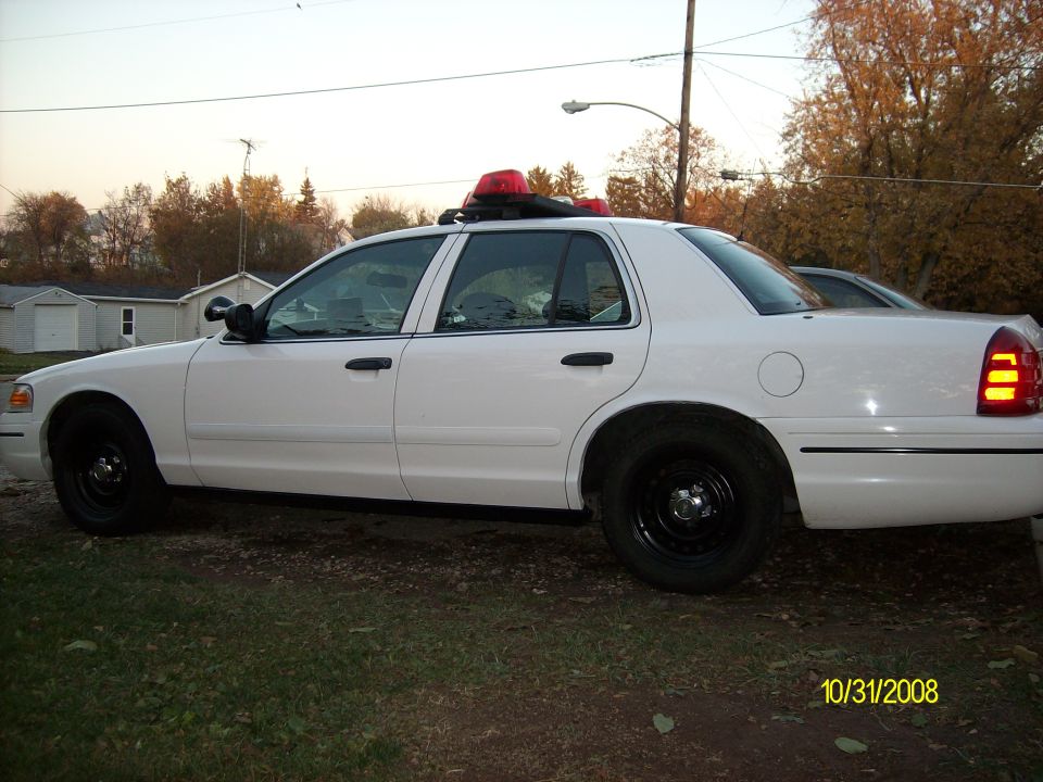 White police car, side view. Red light bar on roof