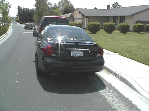 2002 Ford Taurus - Rear view of a 2002 Ford Taurus parked on a residential street. A red truck is in front.