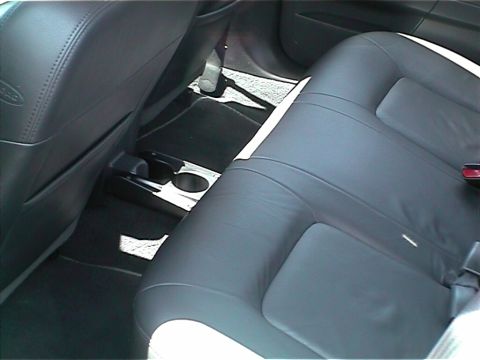 2002 Ford Taurus - The interior of a car with black leather seats and floor mats is shown, with a cup holder in the center console.