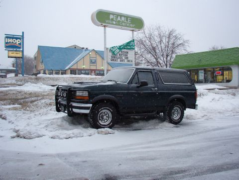 1993 Ford Bronco - A dark green 1993 Ford Bronco is parked in the snow, a brush guard on the front.
