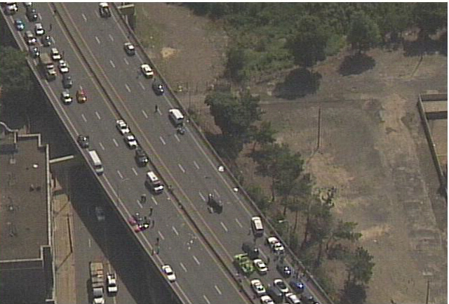Aerial view of a highway accident with multiple vehicles, debris, and emergency personnel
