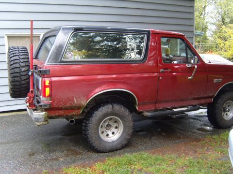 1989 Ford Bronco - This red 1989 Ford Bronco is equipped with a rear-mounted spare tire and off-road tires.