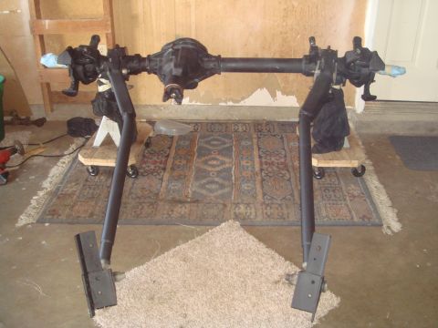 1992 Ford Bronco - A vehicle axle assembly is shown mounted on stands, resting on a rug in a garage setting.