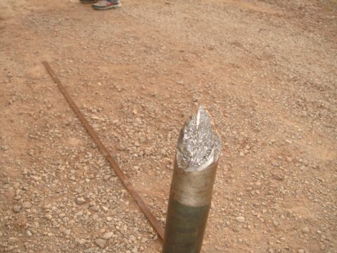 1992 Ford Bronco - A close-up view of a damaged metal drill bit lying on a gravel surface.